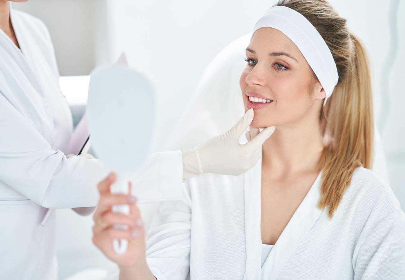 Woman looking at her medical spa treatment results in a handheld mirror
